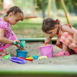 Two girls play in the sandbox