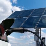 Elektromobil zapojený do domáceho wallboxu napájaného solárnymi panelmi na streche domu